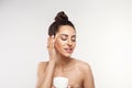 Beauty Woman Concept. Skin care.  Portrait of female model holding and applying cosmetic moisturizing cream and touch own face. Nu Royalty Free Stock Photo
