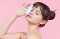 Beauty Woman Face. Close up of young asian woman with fresh skin holding a bottle of cream in hand. girl Applying a Cream Bottle Royalty Free Stock Photo
