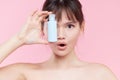 Beauty Woman Face. Close up of young asian woman with fresh skin holding a bottle of cream in hand. girl Applying a Cream Bottle Royalty Free Stock Photo