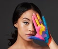 Beauty, woman and face, paint on palm with art, colorful aesthetic and makeup with color in portrait on studio