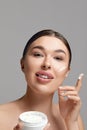 Beauty Woman Face Skin Care. Portrait Of Attractive Young Female Applying Facial Cream And Holding Bottle. Royalty Free Stock Photo