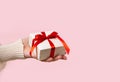 Beauty Woman hands holding Gift box with red bow on pink background, close-up. pastel colors, copy space for text Royalty Free Stock Photo