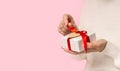 Beauty Woman hands holding and open Gift box with red bow and heart on pink background, close-up. pastel colors, copy Royalty Free Stock Photo