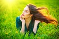 Beauty woman lying on the field enjoying nature. Beautiful brunette girl with healthy long flying hair Royalty Free Stock Photo