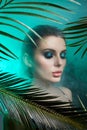 Beauty woman in palm leaves wet makeup, tropical portrait girl in green swimsuit in branches palm tree in studio, smoke and Royalty Free Stock Photo
