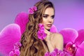 Beauty woman portrait with makeup and long curly hair style with orchid flowers over purple background. Wellness. Smell. Art Photo Royalty Free Stock Photo