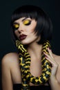 Beauty woman short haircut python yellow snake on her neck. A yellow snake on the shoulders of a girl. Beauty yellow eye shadow