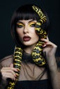Beauty woman short haircut python yellow snake on her neck. A yellow snake on the shoulders of a girl. Beauty yellow eye shadow
