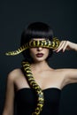 Beauty woman short haircut python yellow snake on her neck. A yellow snake on the shoulders of a girl. Beauty yellow eye shadow