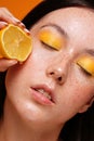 Beauty woman squeezing juicy lemon fruit on her healthy skin with natural freckles Royalty Free Stock Photo