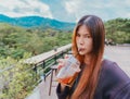 Beauty Young female with funny face is sitting in Cafe with forest and mountain nature background while drinking iced