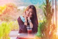 Beauty Asian smiling female is sitting in Cafe with forest nature background with Iced coffee on the table