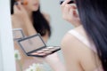 Beauty young asian woman happy and smile with face looking mirror applying makeup with brusher of cheek in the room Royalty Free Stock Photo