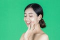 Beauty young Asian woman touching her face over green isolated background. Healthy skin care concept Royalty Free Stock Photo