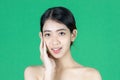 Beauty young Asian woman touching her face over green isolated background. Healthy skin care concept Royalty Free Stock Photo