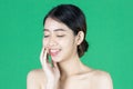 Beauty young Asian woman touching her face over green isolated background. Healthy skin care concept Royalty Free Stock Photo