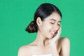 Beauty young Asian woman touching her face over green isolated background. Healthy skin care concept Royalty Free Stock Photo