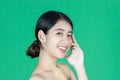 Beauty young Asian woman touching her face over green isolated background. Healthy skin care concept Royalty Free Stock Photo