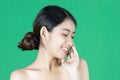 Beauty young Asian woman touching her face over green isolated background. Healthy skin care concept Royalty Free Stock Photo