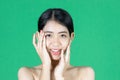 Beauty young Asian woman touching her face over green isolated background. Healthy skin care concept Royalty Free Stock Photo