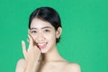 Beauty young Asian woman touching her face over green isolated background. Healthy skin care concept Royalty Free Stock Photo