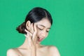 Beauty young Asian woman touching her face over green isolated background. Healthy skin care concept Royalty Free Stock Photo