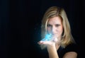 Beauty young blond hair woman holding small glowing blue dinosaur, dragon. Photomanipulation glowing animal on black background Royalty Free Stock Photo