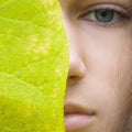 Beauty young blonde woman with green eyes without make up. Teen girl model and big green leaf Royalty Free Stock Photo