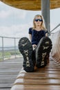 Beauty young caucasian blonde woman sit on bench, focus to shoes