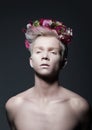 Beauty. Young Man with Wreath of Flowers over Gray