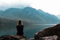 Beauty young woman from back sitting on rock at Vorderer langbathsee lake in Austria Alp mountain