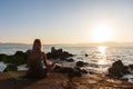Beauty young woman in dress sitting on rock in yoga pose near sea at sunset. Fitness, meditation background, Croatia Royalty Free Stock Photo