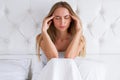 Beauty, young woman with headache. Upset woman having a migraine lying on a bed at home