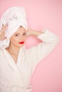 Beauty Young woman with red lips standing in the bath robe on the pink background Royalty Free Stock Photo