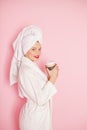 Beauty Young woman with red lips standing in the bath robe and towel on the head on the pink background. Studio shot Royalty Free Stock Photo