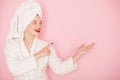 Beauty Young woman with red lips standing in the bath robe and towel on the head on the pink background. Studio shot Royalty Free Stock Photo