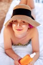 Beauty Young woman with sun cream on face holding sunscreen bottle on the beach. Royalty Free Stock Photo