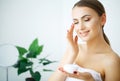 Beauty Youth Skin Care Concept - Close up Beautiful Caucasian Woman Face Portrait applying some cream to her face for skin care. Royalty Free Stock Photo