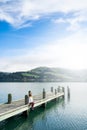 Beautyful asian woman resting is looks at the sea bay with houses and boats on a sunny day at Childrens bay, Akaroa, Canterbury, Royalty Free Stock Photo