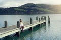 Beautyful asian woman resting is looks at the sea bay with houses and boats on a sunny day at Childrens bay, Akaroa, Canterbury, Royalty Free Stock Photo