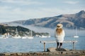 Beautyful asian woman resting is looks at the sea bay with houses and boats on a sunny day at Childrens bay, Akaroa, Canterbury, Royalty Free Stock Photo