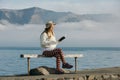 Beautyful asian woman resting is looks at the sea bay with houses and boats on a sunny day at Childrens bay, Akaroa, Canterbury, Royalty Free Stock Photo