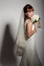 A beautyful bride looks down at her bouquet from roses.