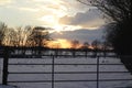 A beautyful sunset with cloudy sky a cattle gate in the foreground