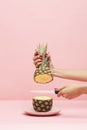 Hands with knife cutting a Pineapple on a pink background