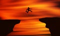 Brave Man jumping off The Cliff In Front of Beautiful orange Sunset. Royalty Free Stock Photo