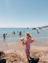 Becici, Montenegro - 03 august 2023: Little girl in a swimsuit with inflatable armlets stands by the sea and looks at Royalty Free Stock Photo