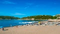 Resting people on public sandy beach at a sunny summer morning. Becici, Montenegro