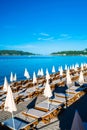 Sun loungers and umbrellas on public beach at summer sunny mornin. Skojl island background. Calm sea and blue sky