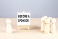 BECOME A SPONSOR text on easel with wooden figure, meeting concept